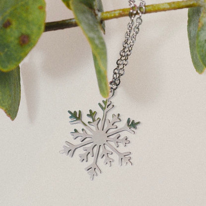 
“Collar en forma de copo de nieve de acero inoxidable, colgado de una rama, con un diseño inspirado en la ciudad de Burgos.”