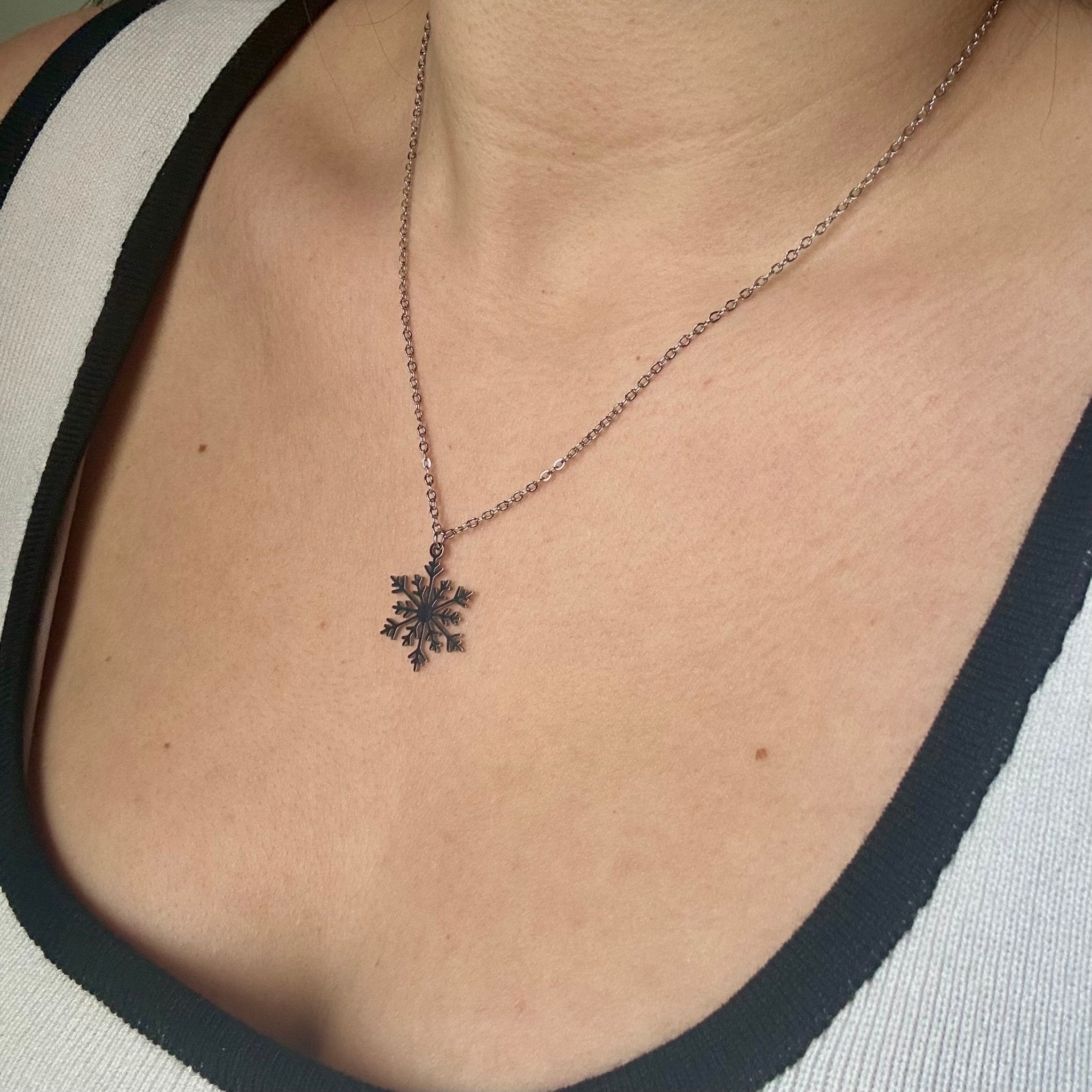 (collar puesto en el cuello de una persona):
“Collar copo de nieve de acero inoxidable sobre el cuello de una persona, destacando su diseño delicado y elegante.”